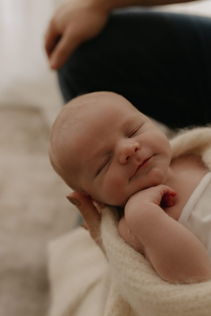 baby boy smiling with hand under chin