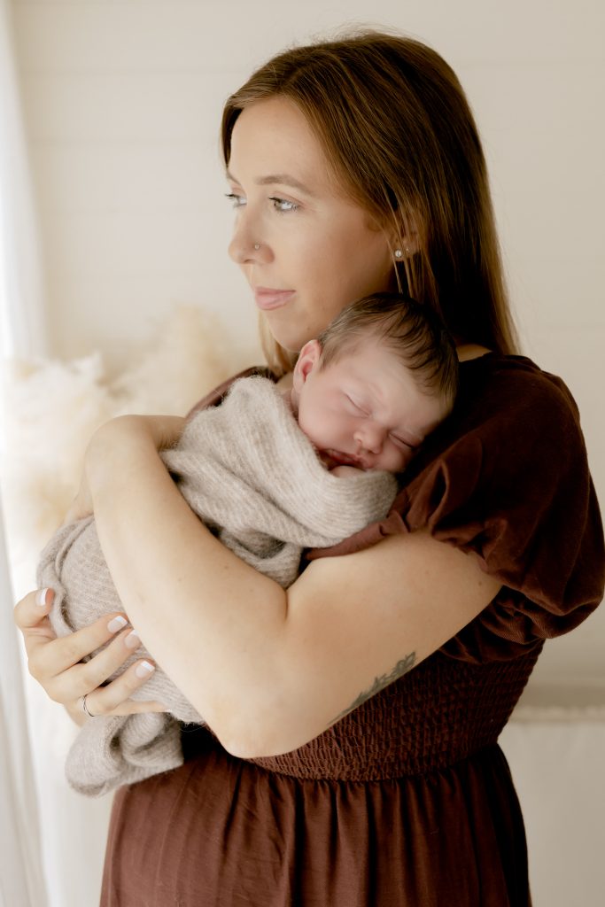 mum holding her sleeping baby girl, looking out the window