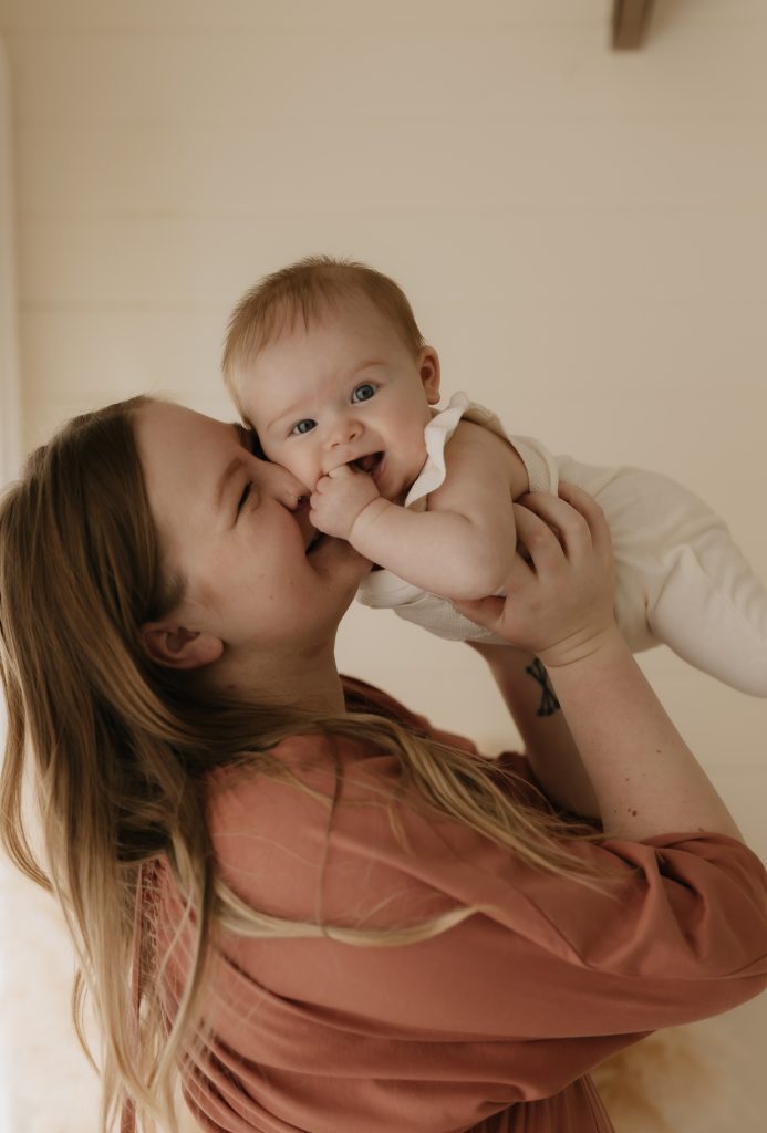 Mum holding baby girl in the air for photoshoot